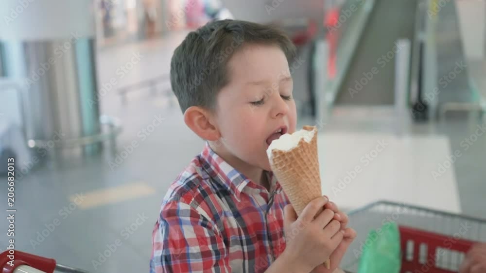 Happy little boy in shopping cart with tasty ice cream during family shopping in hypermarket Happy little boy in shopping cart with tasty ice cream during family shopping in hypermarket