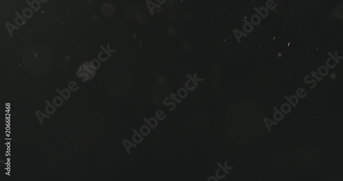 dust particles floating over black background with motion blur