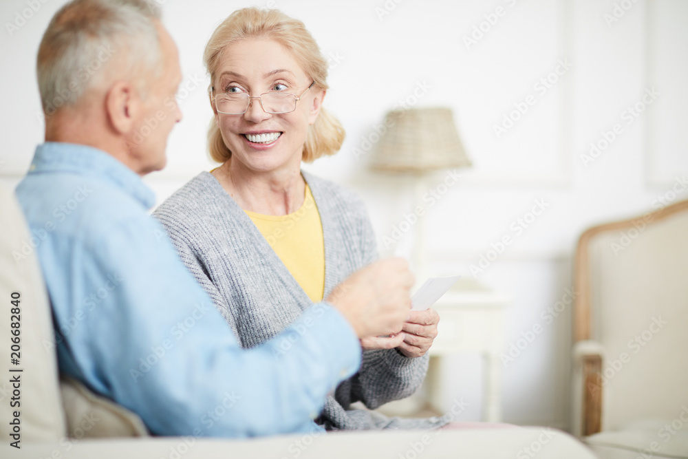 Happy aged woman with toothy smile looking at her husband during conversation at home Happy aged woman with toothy smile looking at her husband during conversation at home