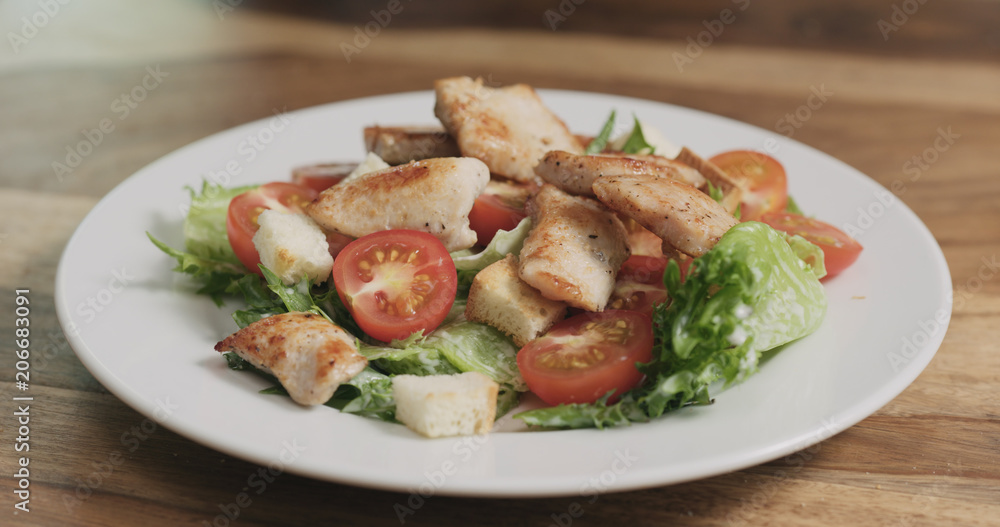 closeup adding chicken to caesar salad closeup adding chicken to caesar salad