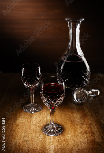 2 glasses of port and a decanter on an antique wooden table.