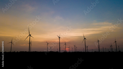 Wind turbine farm and agricultural fields with rays of light at sunset