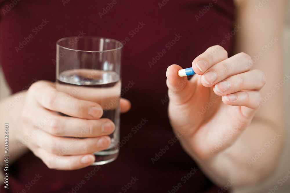 young woman holding pill and glass of water young woman holding pill and glass of water