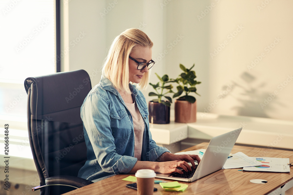 Young businesswoman working online at her desk in an office Young businesswoman working online at her desk in an office