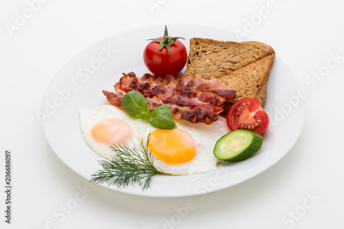 Fried eggs with bacon on the wooden table.
