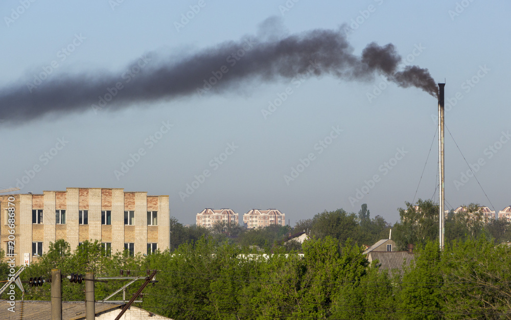 Smoke from industrial chimneys against the blue sky. Pollution.