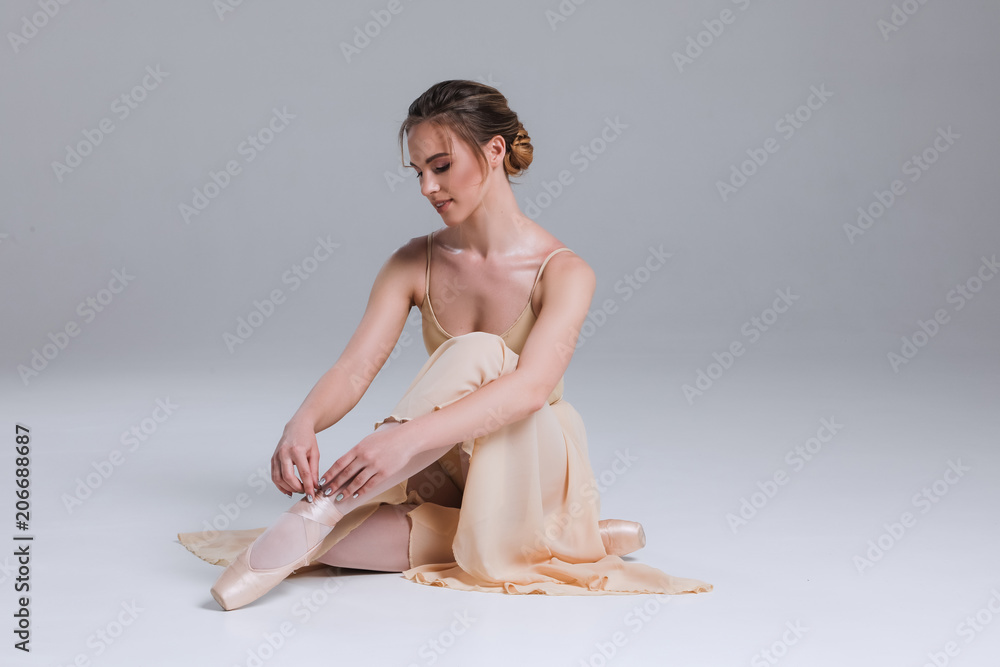 Foto Stock Enjoy your relaxation! Side view portrait of the young ballerina  sitting on the floor in the modern dancing studio and posing at the camera.  | Adobe Stock
