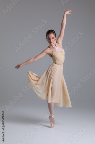 Dance to freedom! Attractive delicate tender slim young female ballet dancer practicing her movements on the isolated background.
