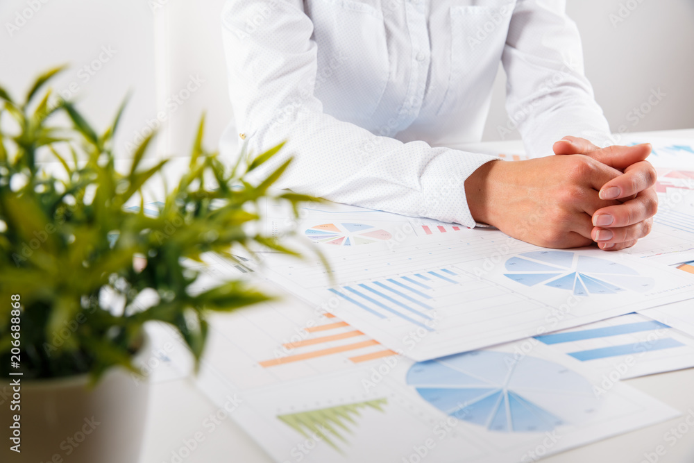 Business woman pointing at graph document close-up. Young business woman showing financial diagram, graph, business charts during conference sitting at the office desk Business woman pointing at graph document close-up. Young business woman showing financial diagram, graph, business charts during conference sitting at the office desk