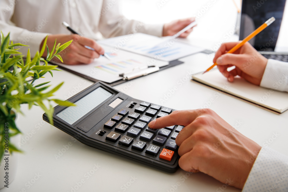 Business team two colleagues discussing new plan financial graph data on office table with laptop and calculator Business team two colleagues discussing new plan financial graph data on office table with laptop and calculator