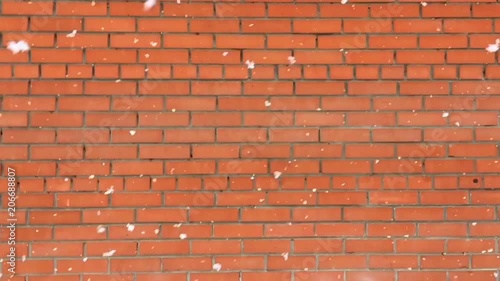 Snowflakes slowly falling against a backdrop of brick wall photo