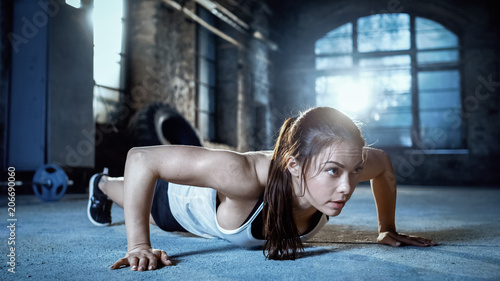 Athletic Beautiful Woman Does Push-ups as Part of Her Cross Fitness  Bodybuilding Gym Training Routine.