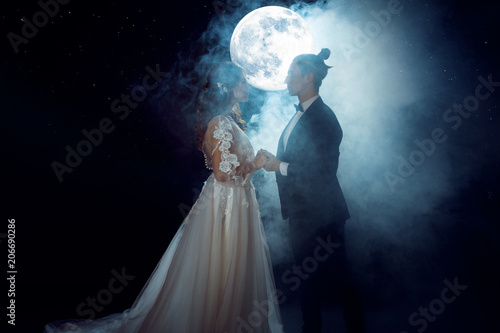 Mysterious and romantic meeting, the bride and groom under the moon. Hugs together. Mixed media