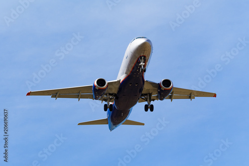 Bottom view of a dark silhouette of flying passenger aircraft a background of blue sky