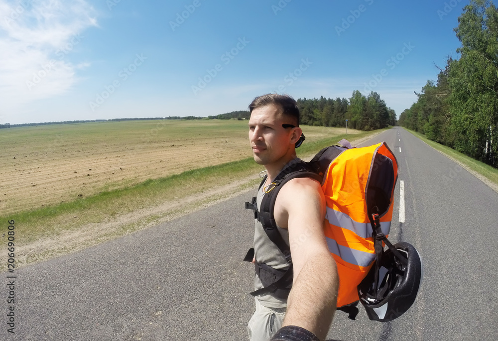 The young man stands in the middle of the highway and looks away, enjoying the fresh air. The young man stands in the middle of the highway and looks away, enjoying the fresh air.