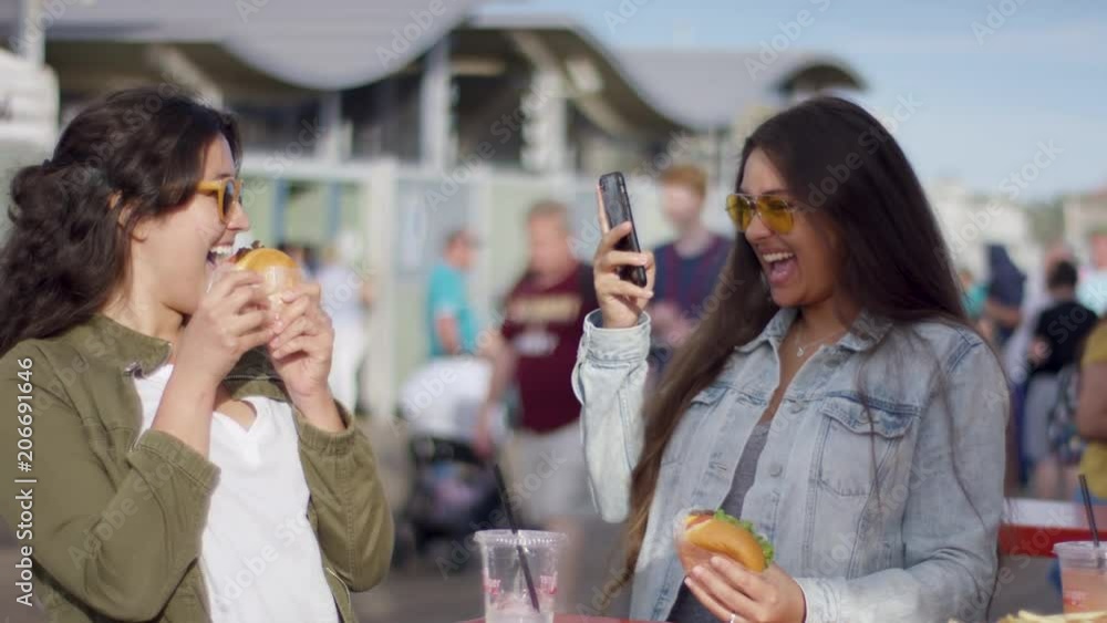 Excited Tourist Takes A Photo Of Her Friend Posing With Her Burger For Social Media (Shot On Red Scarlet-W Dragon In 4K, Slow Motion) Excited Tourist Takes A Photo Of Her Friend Posing With Her Burger For Social Media (Shot On Red Scarlet-W Dragon In 4K, Slow Motion)