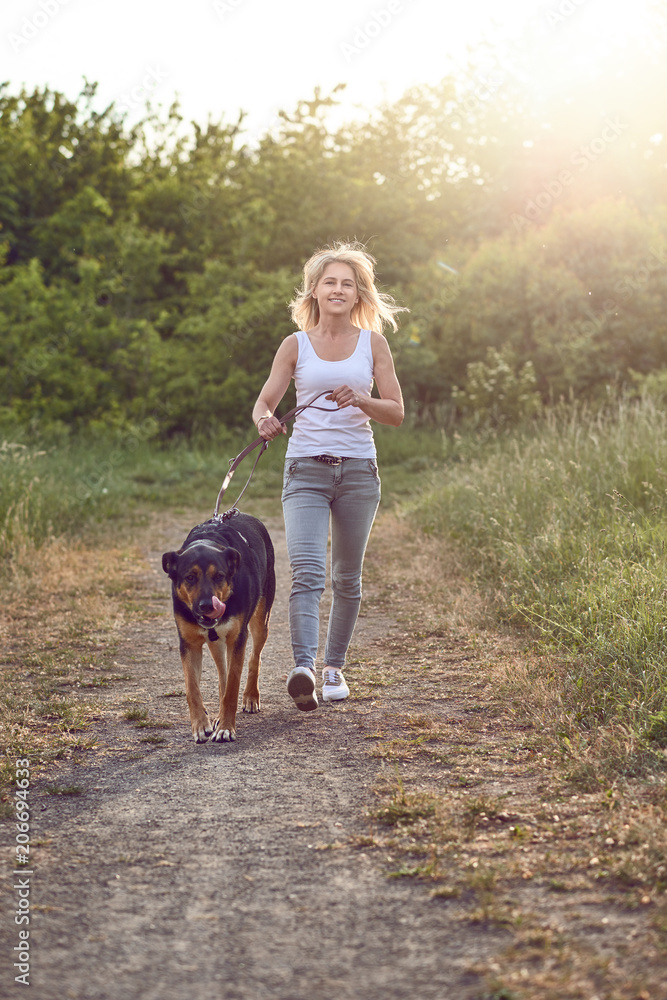 Frau im mittleren Alter geht mit ihrem Hund spazieren Frau im mittleren Alter geht mit ihrem Hund spazieren