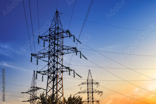 High-voltage power lines at sunset. Electric transmission towers.