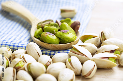 Pistachios in the wooden spoon on the wood table.