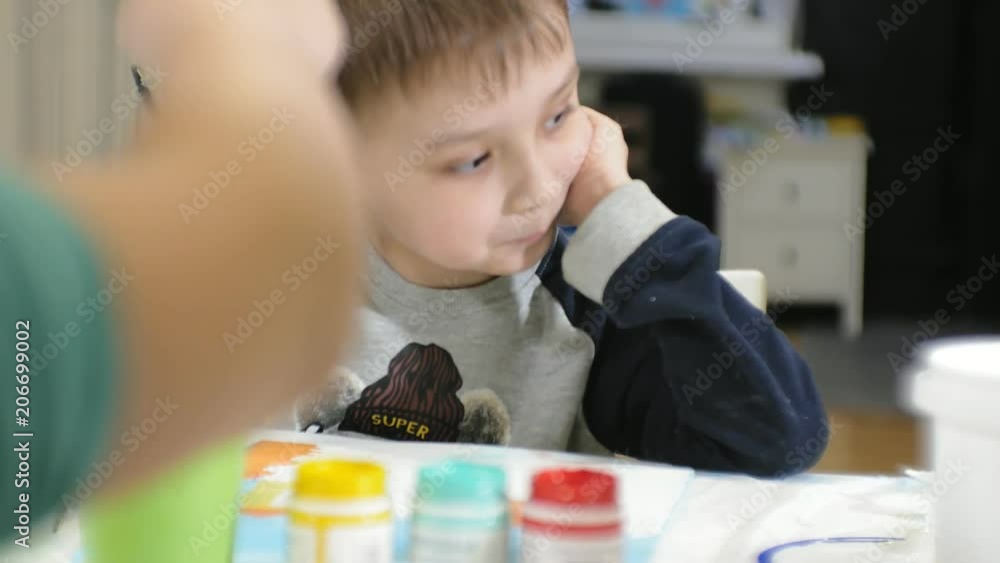 Children boys and girls sitting together around the table in classroom and drawing. With them is their young and beautiful teacher. Children boys and girls sitting together around the table in classroom and drawing. With them is their young and beautiful teacher.
