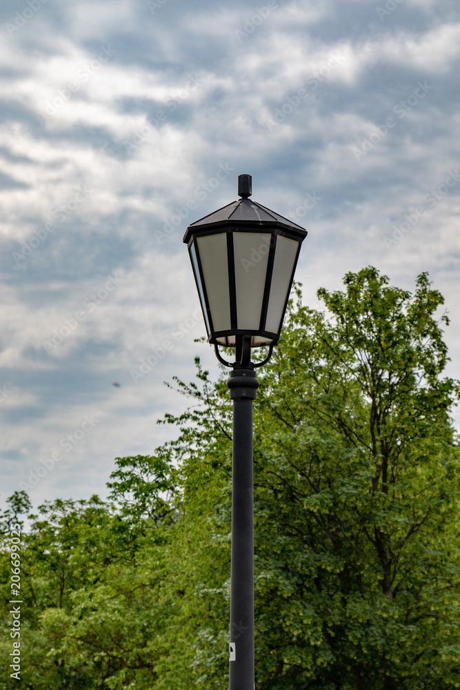 Old single street lamp in front of a cloudy sky in summer 
