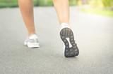 Female runner feet jogging on street.