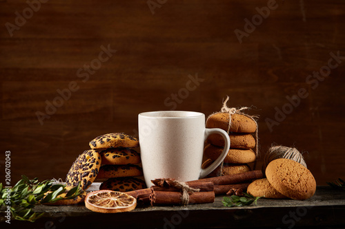 Traditional Christmas tea concept with a cup of hot tea, cookies and decorations on a wooden table, selective focus