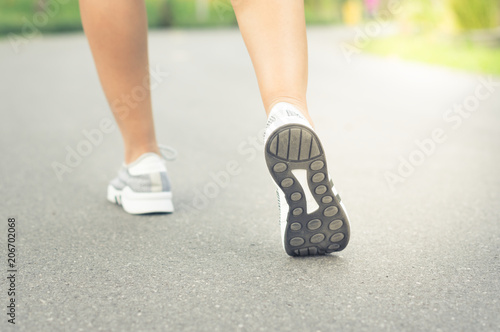 Female runner feet jogging on street.