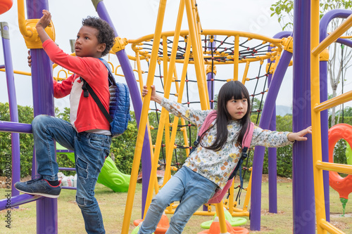 Canvas Print Two kids boy and girl having fun to play on children's climbing toy at school playground,back to school activity