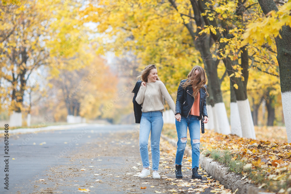 Young pretty girls having fun outdoors in autumn background. Cheerful friends in the fall time Young pretty girls having fun outdoors in autumn background. Cheerful friends in the fall time