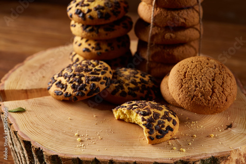 Sweet assortment of biscuits on a round wood log over rustic wooden background, close-up, selective focus.