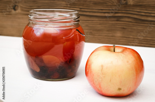 Compote stewed fruit drink in the glass bank with fresh apple on white table background.