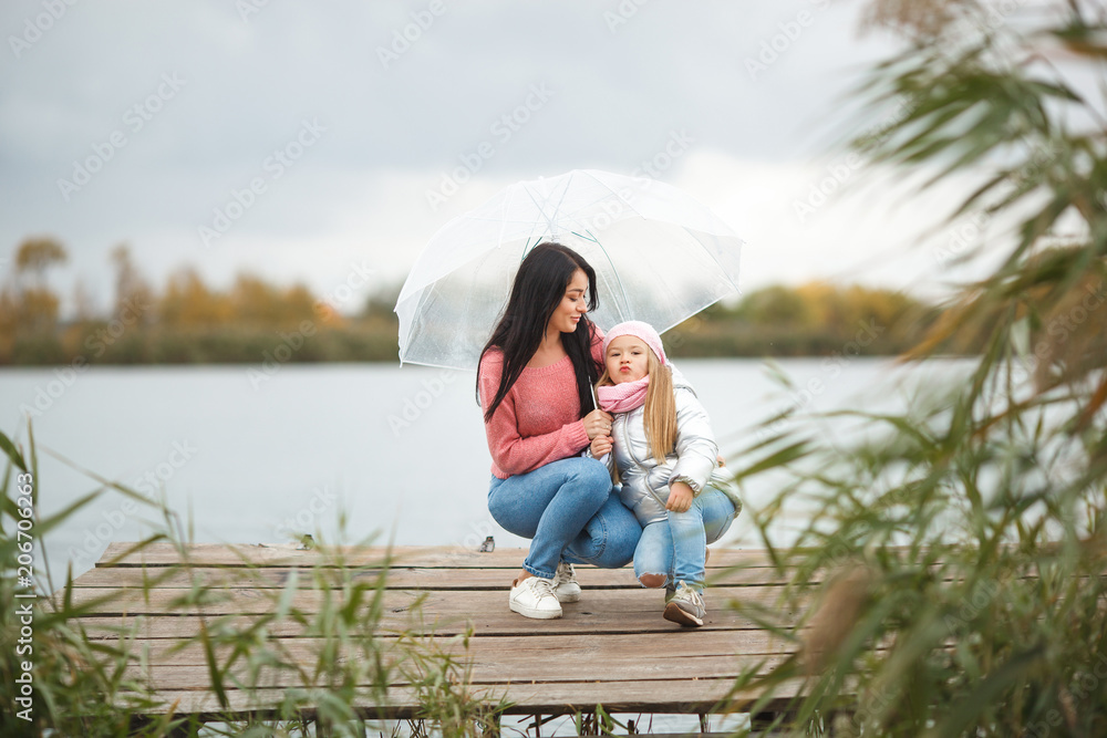 Fototapeta premium Young mother with her little daughter in the fall time near the lake