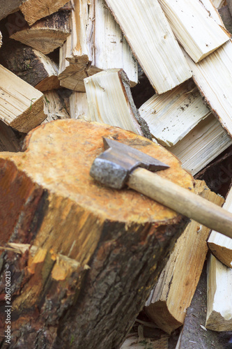 Chopped firewood. The ax with the wooden handle does not have a focus.