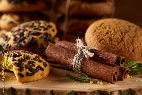 Sweet assortment of biscuits on a round wood log over rustic wooden background, close-up, selective focus.