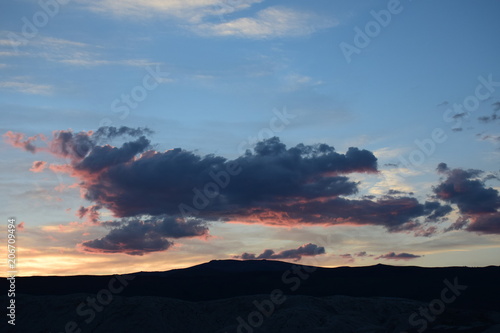 Dramatic colorful sunset clouds over a hilly horizon