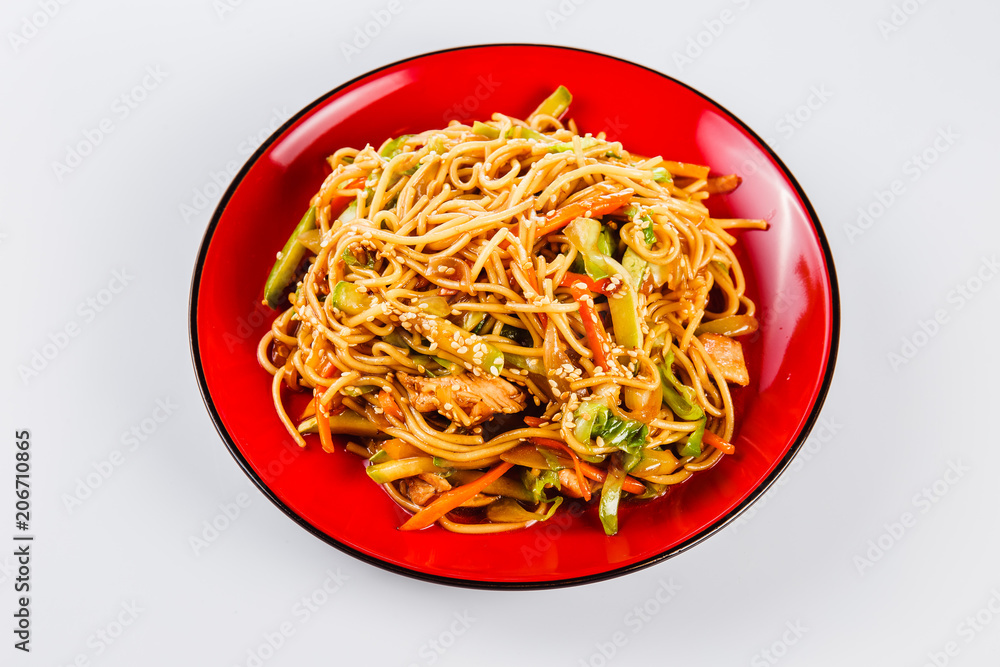 Noodles with pork, pepper and sesame seeds on a red plate on a white background. Traditional Italian pasta. Close Noodles with pork, pepper and sesame seeds on a red plate on a white background. Traditional Italian pasta. Close
