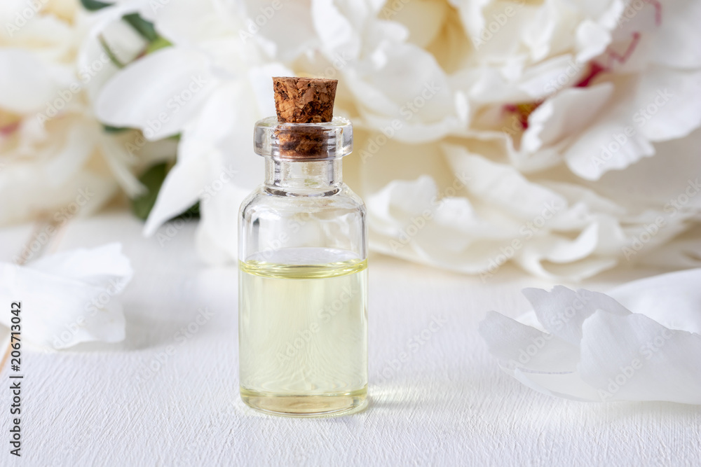 A bottle of essential oil with fresh peony flowers A bottle of essential oil with fresh peony flowers