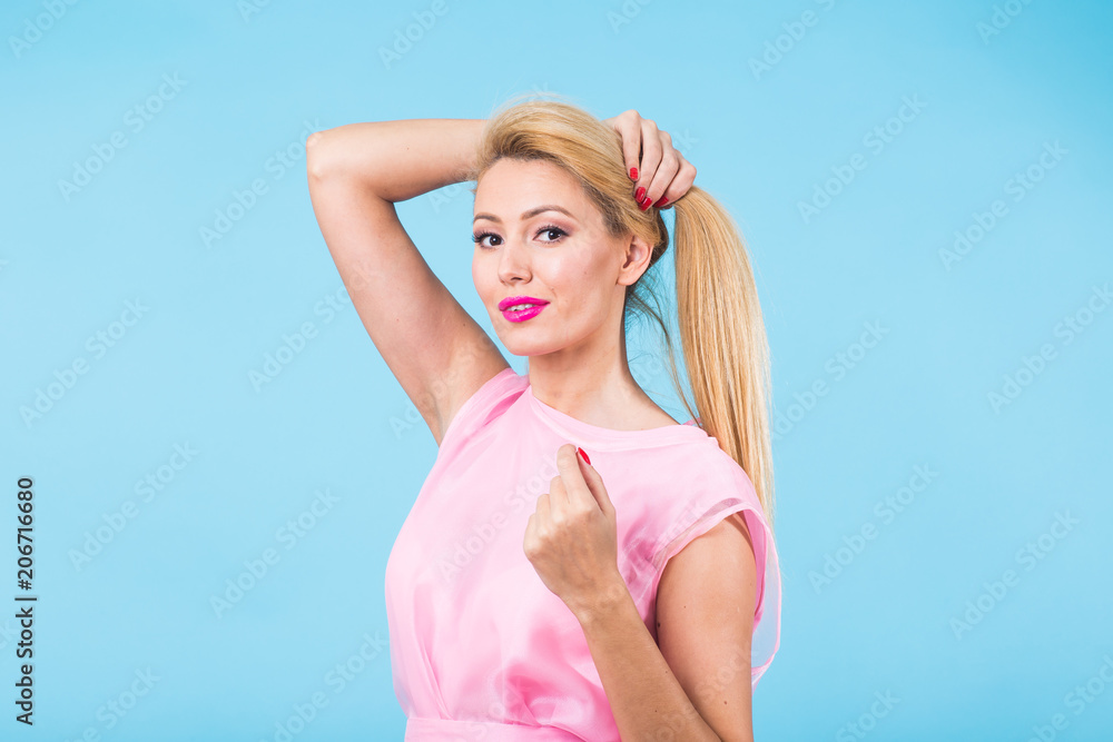 Beautiful woman with long straight blond hair. Fashion model posing at studio on blue background