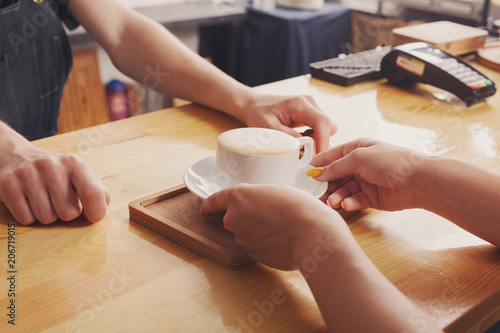 Barista serving coffee cup on wooden bar counter © Prostock-studio