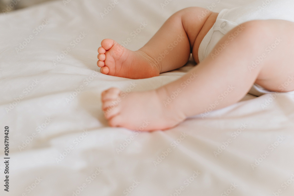 partial view of baby in bodysuit lying on bed partial view of baby in bodysuit lying on bed