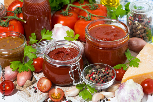 tomato sauces, pasta and fresh ingredients on wooden background