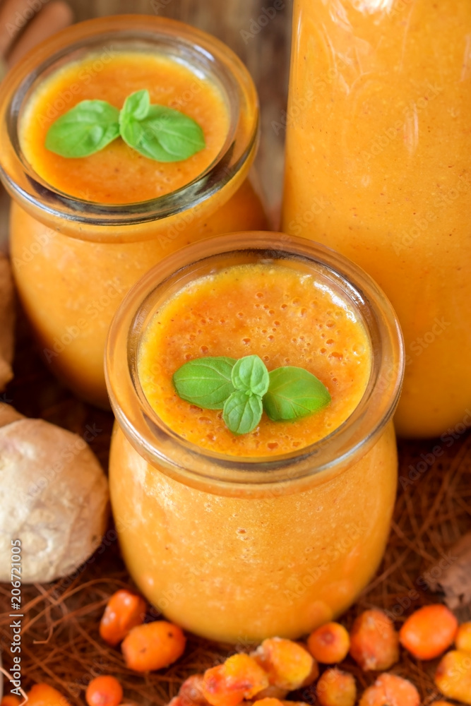 Yellow smoothie with berries of sea buckthorn in glass jars decorated with mint Yellow smoothie with berries of sea buckthorn in glass jars decorated with mint