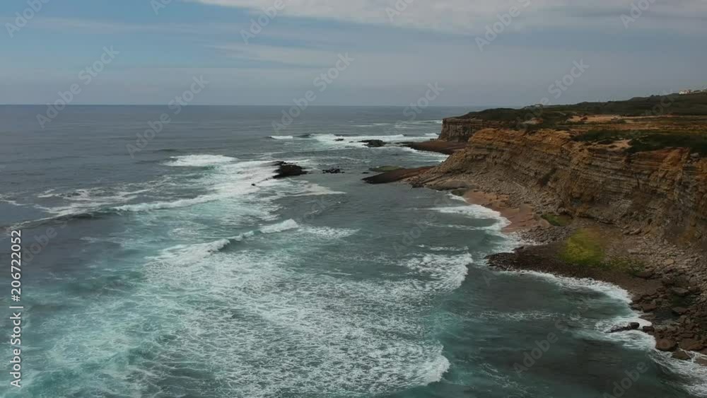 Aerial view of a cliff in the portuguese coastline with ocean waves and brown rocks Aerial view of a cliff in the portuguese coastline with ocean waves and brown rocks