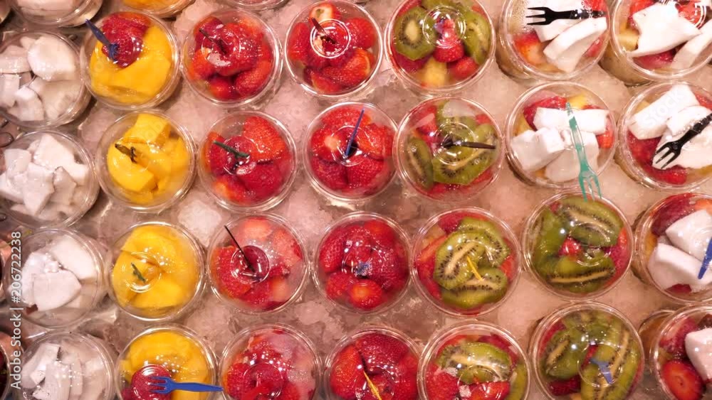 Fresh sliced fruit in plastic cups on a stand at La Boqueria market, Barcelona Fresh sliced fruit in plastic cups on a stand at La Boqueria market, Barcelona