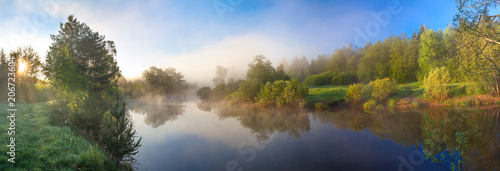 rural panorama with river, fog and forest at sunrise