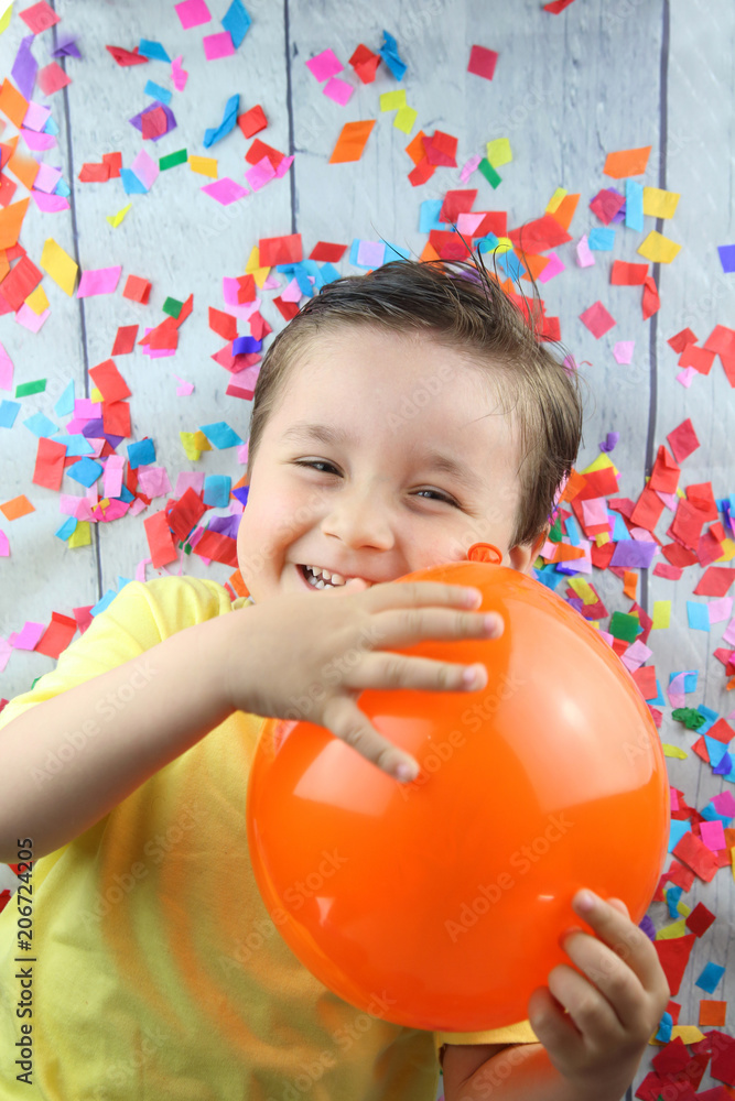 niño feliz jugando con un globo en un suelo lleno de confetti Stock