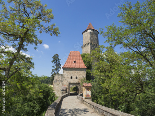 medieval castle Zvikov Klingenberg main entry gate with round tower and stone bridge  green trees blue sky  castle is placed at confluence of the Vltava and Otava rivers  Czech Republic  vertical view
