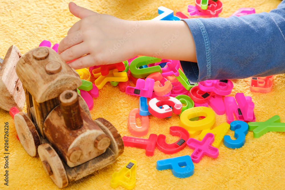 Little baby hand playing with colorful toys and letters