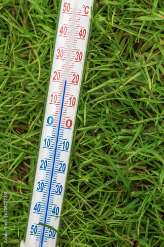 Thermometer for measuring weather temperature against the background of green grass and accessories for summer recreation 